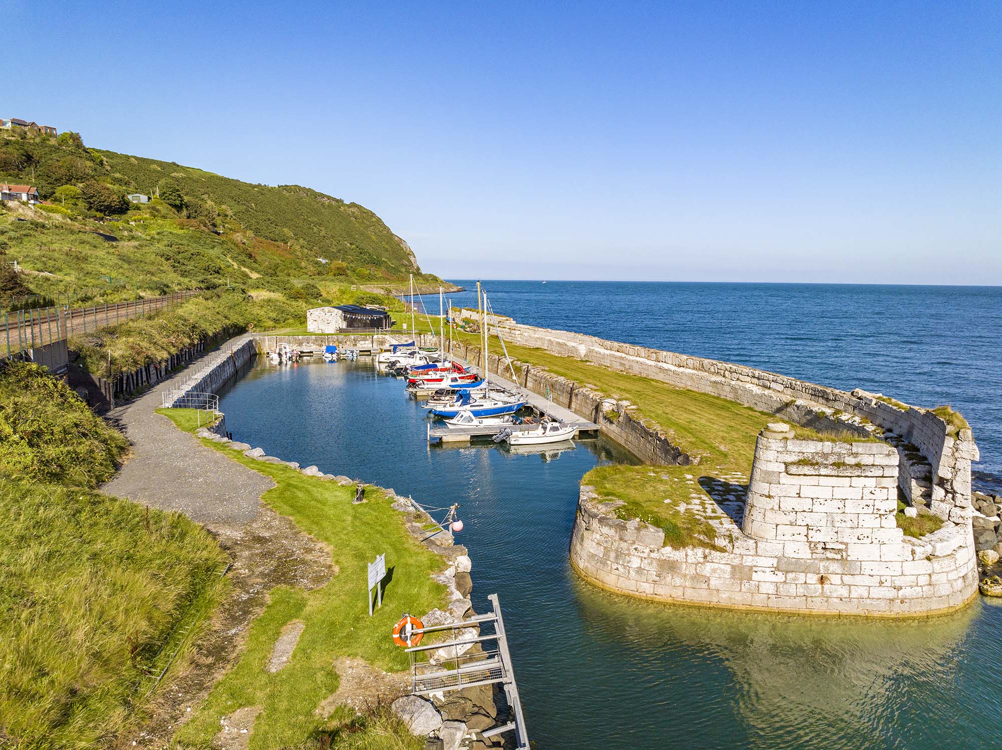 Sunny day at Whiteharbour dock with small boats moored at the pier in Whitehead, Northern Ireland